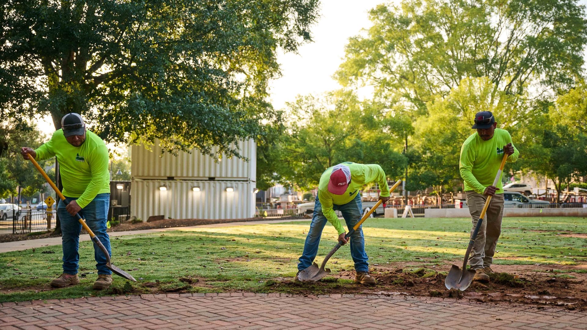 Landscaping crew digging and preparing soil along a walkway during commercial landscape installation.